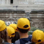bambini con cappellino giallo in gita davanti ad un monimento